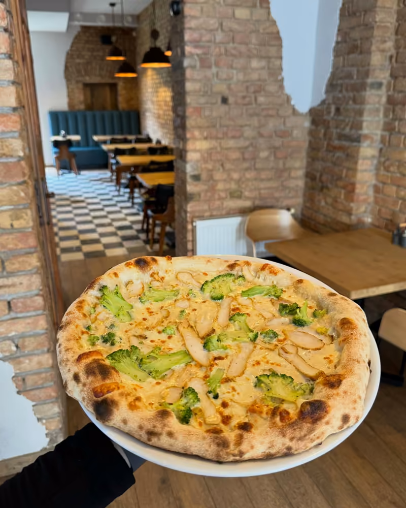 Pizza Pollo con broccoli na tle ceglanej sali lokalu na Deptaku Bogusława