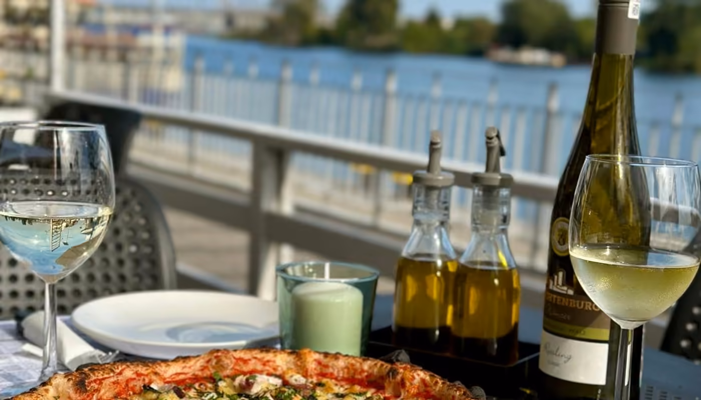 Pizza i kieliszki wina na stoliku tarasu, w tle Odra